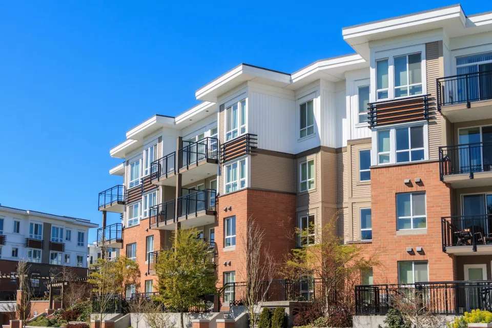Four-story modern apartment complex with white stucco and red brick.